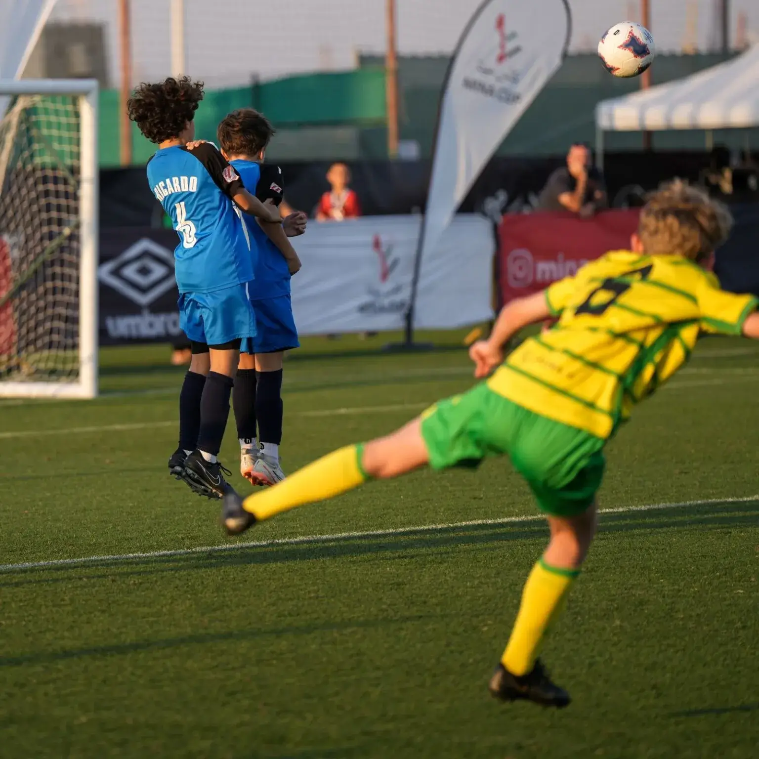 A diverse group of individuals playing soccer on a grass field at Mina Cup 2024.