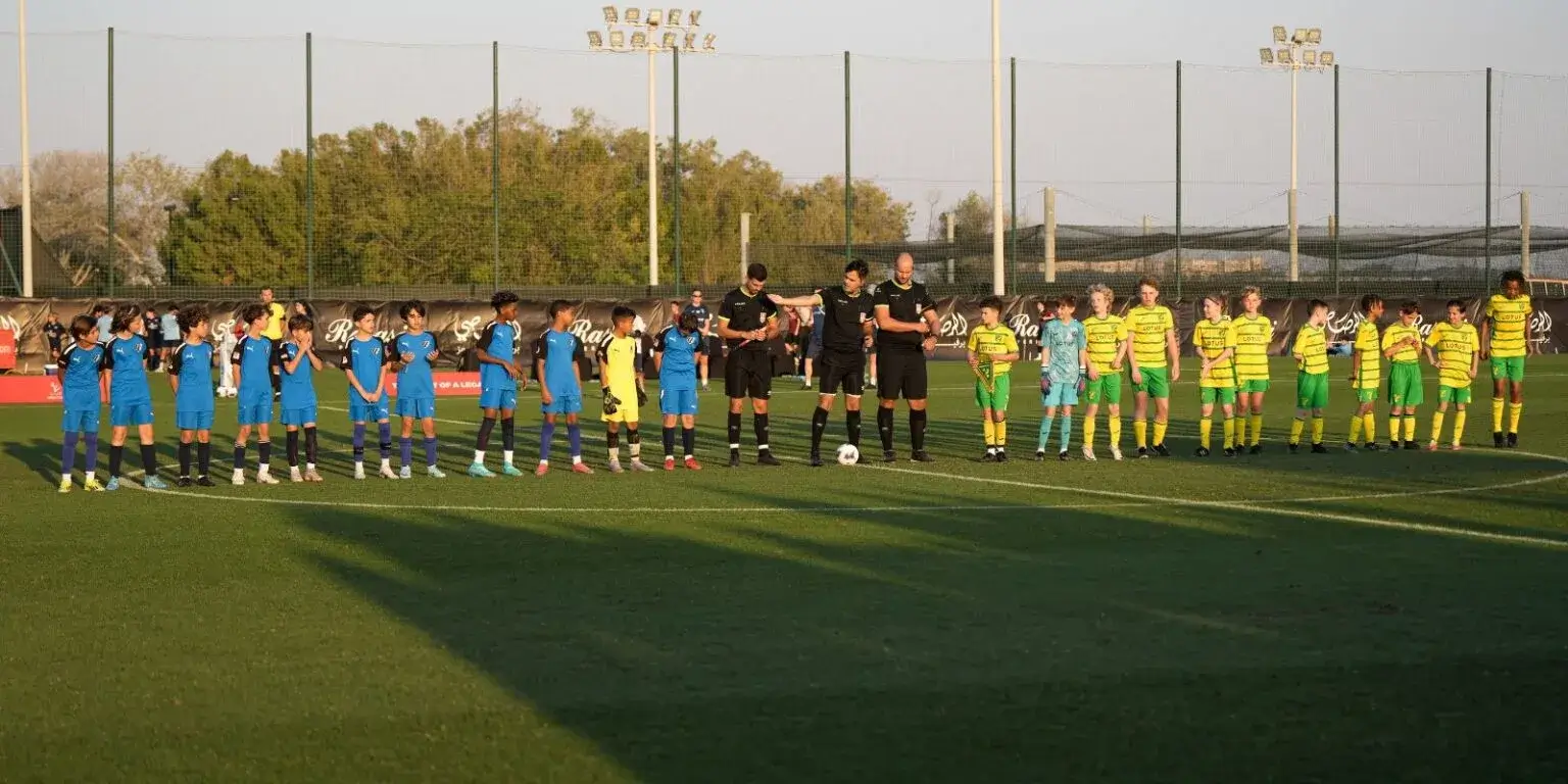 A group of soccer players standing on the field during the Mina Cup.