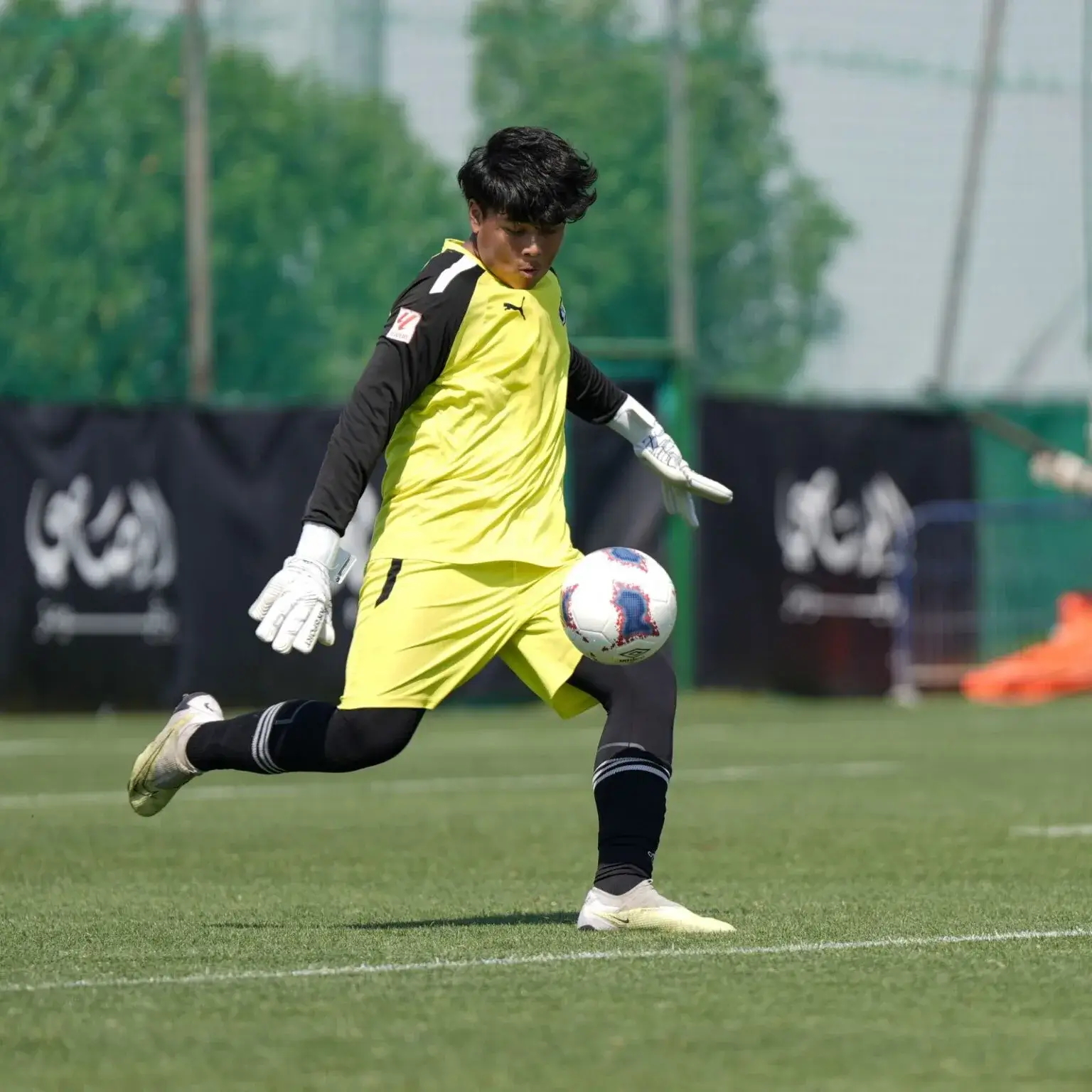 A man kicking a soccer ball on a grass field | Mina Cup 2024.