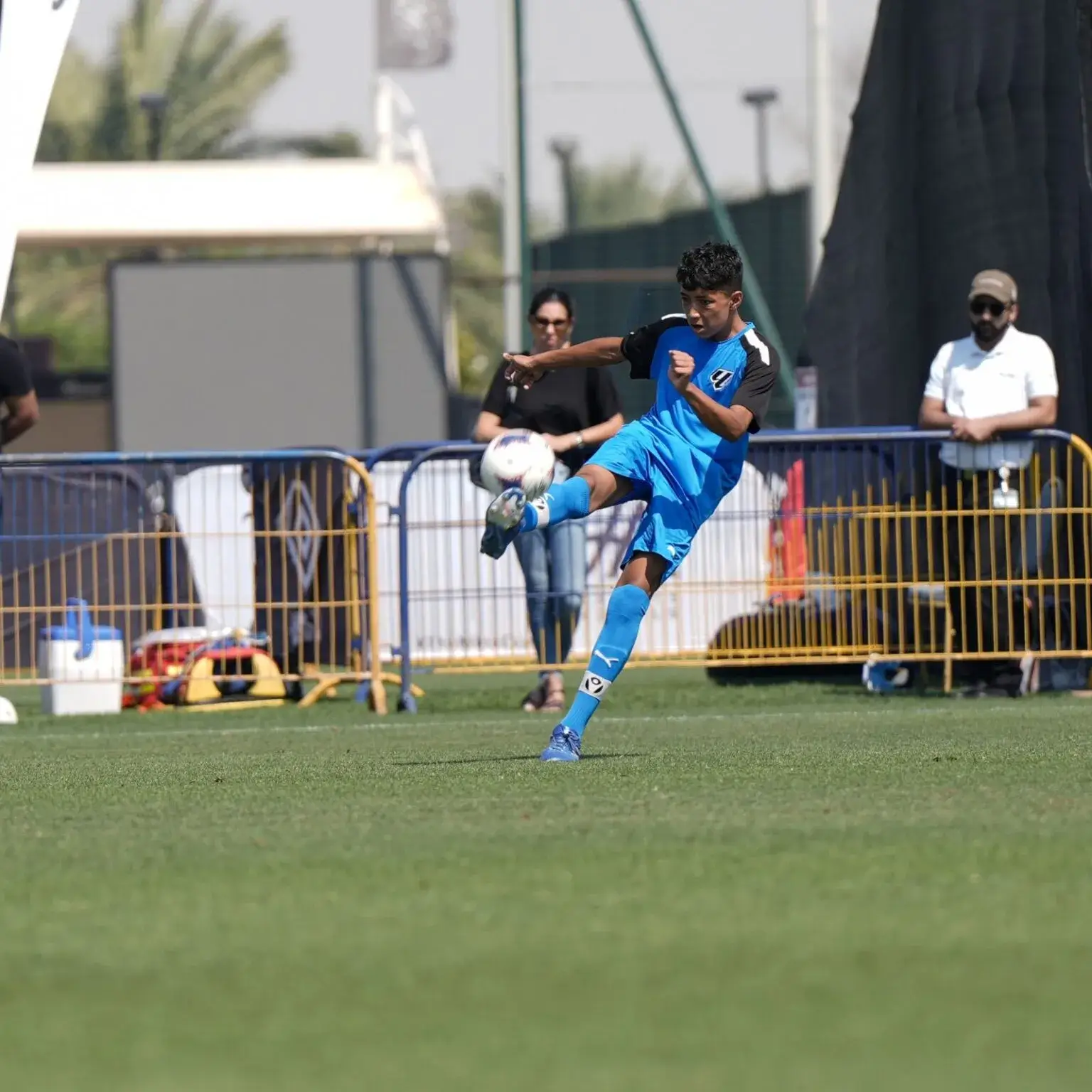 Mina Cup 2024 | A player in blue kicking a soccer ball on a grass field