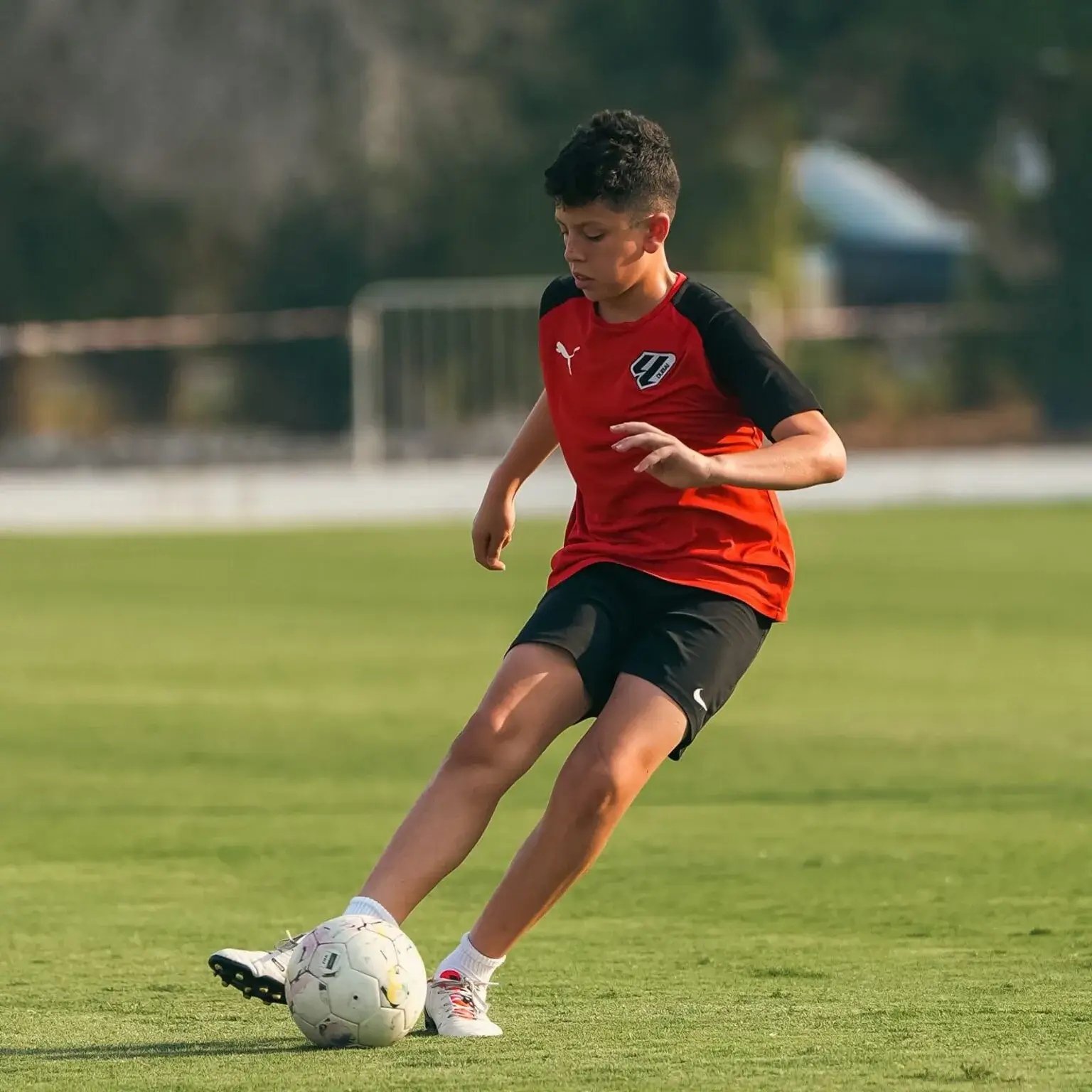 A young boy happily playing football during a training session before IBER Cup.