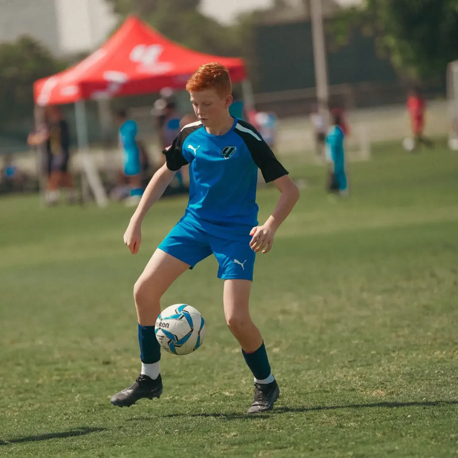 DOFA Season 2023 | A young boy in blue jersey kicking a soccer ball