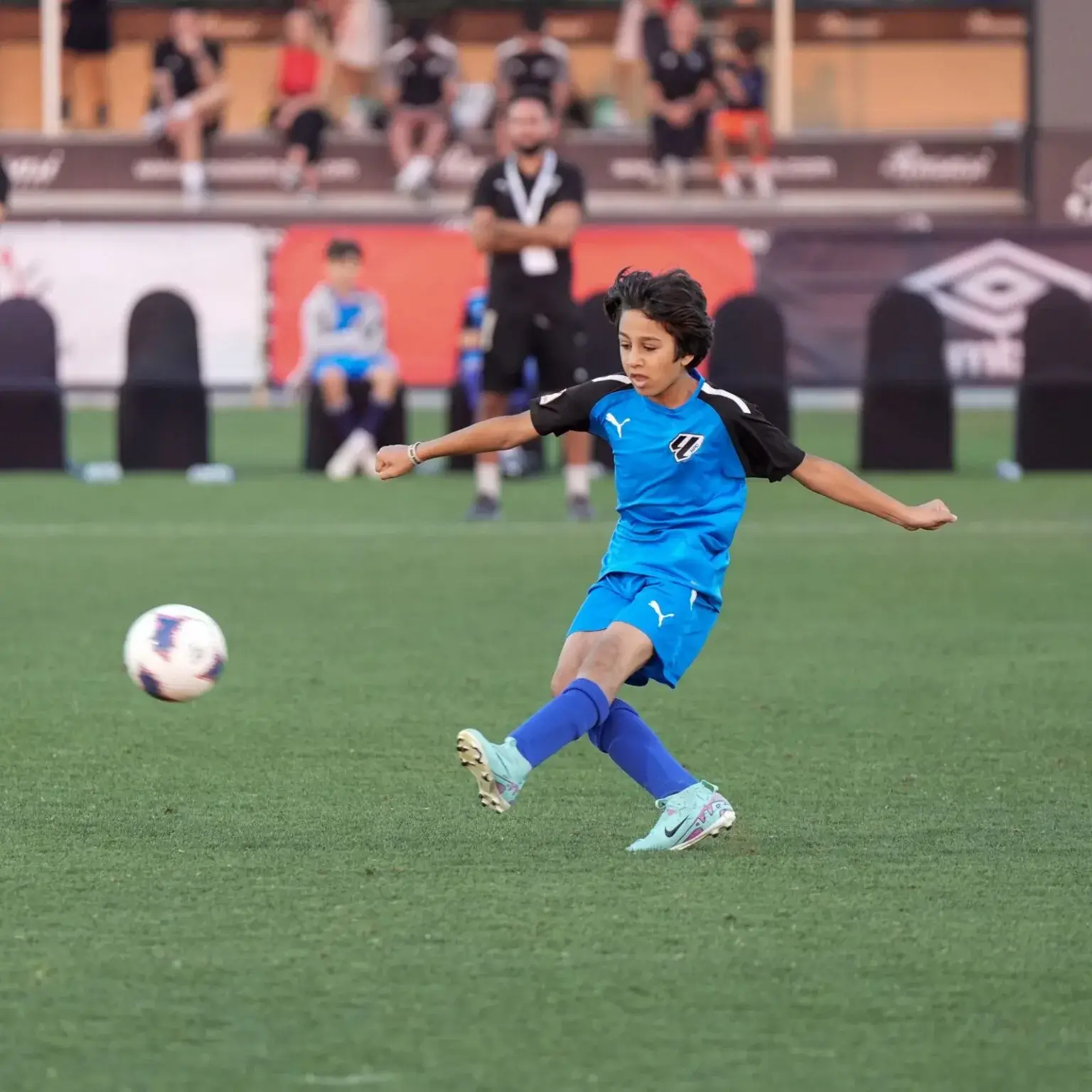 A young boy kicking a soccer ball on a field.