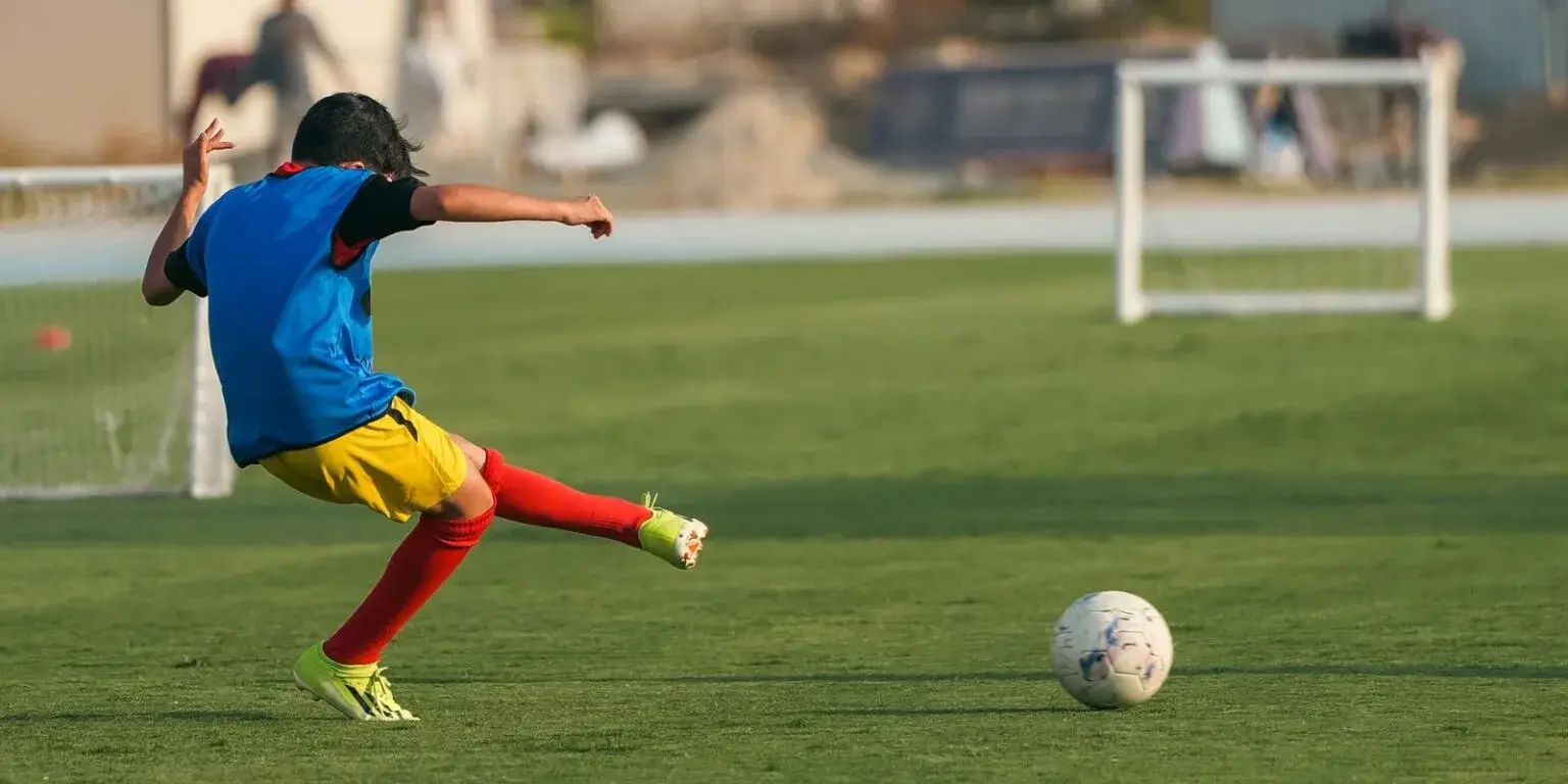 A young man kicks a soccer ball on a field during the last training session before IBER Cup.