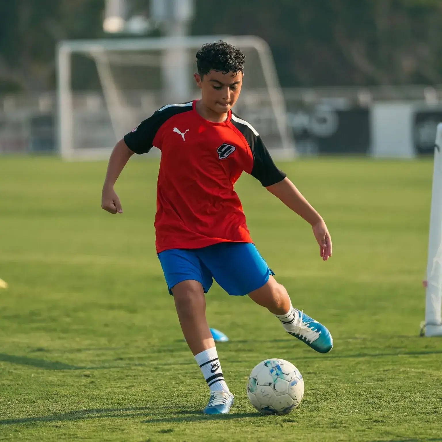 Boy playing footall on field in preparation for IBER Cup training session.