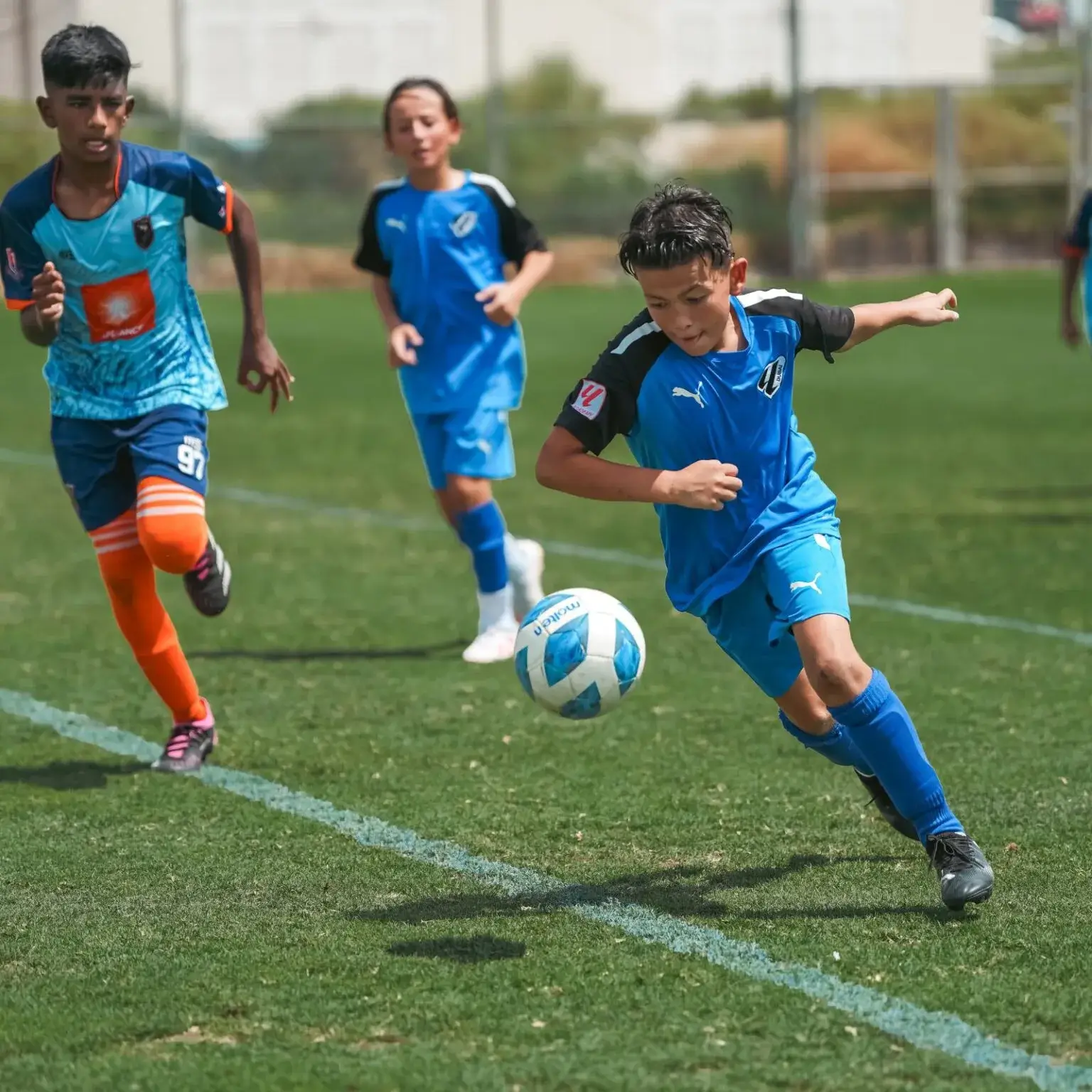 Children playing football on a grass field, kicking a ball and having fun DOFA Season.