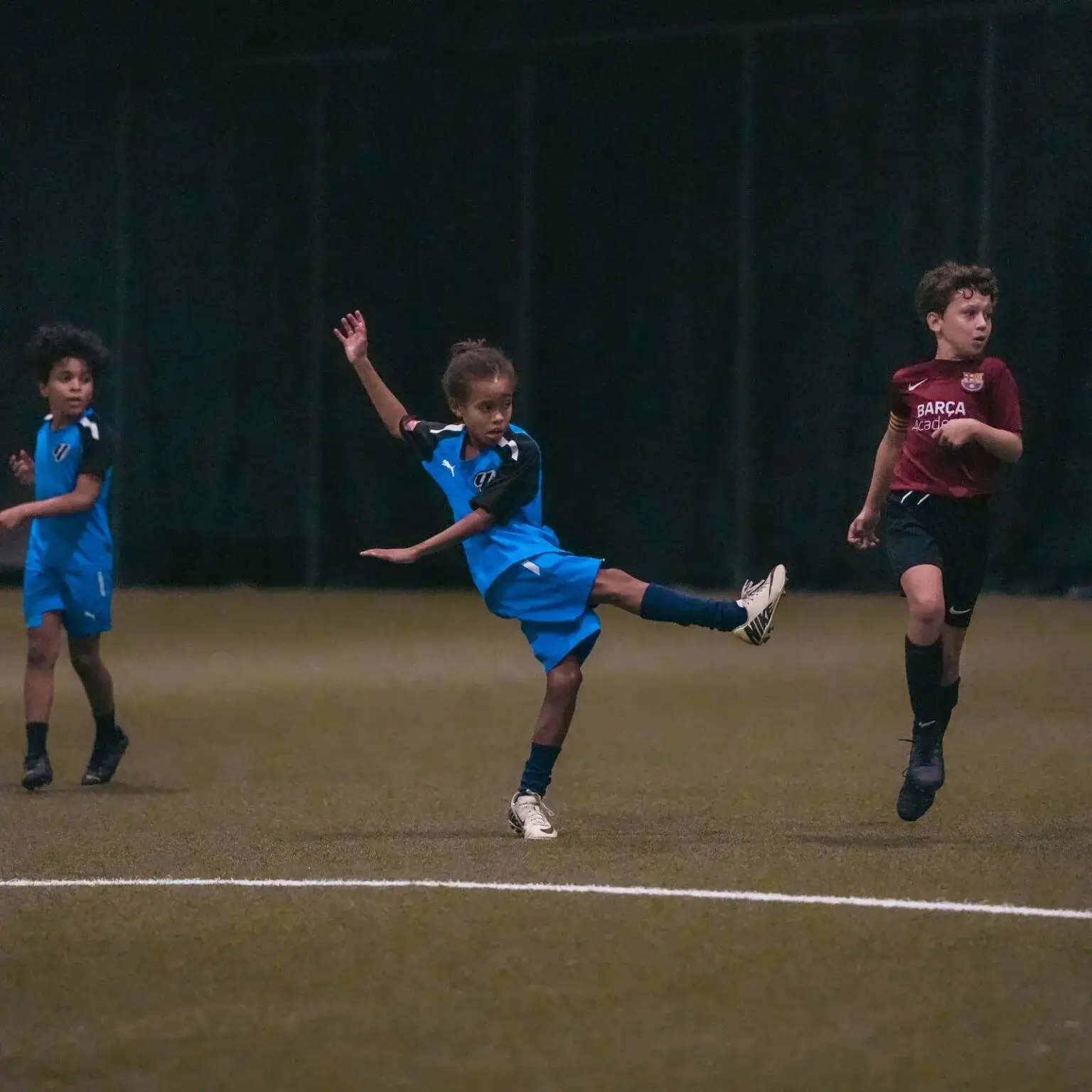 Children playing soccer on a grass field.