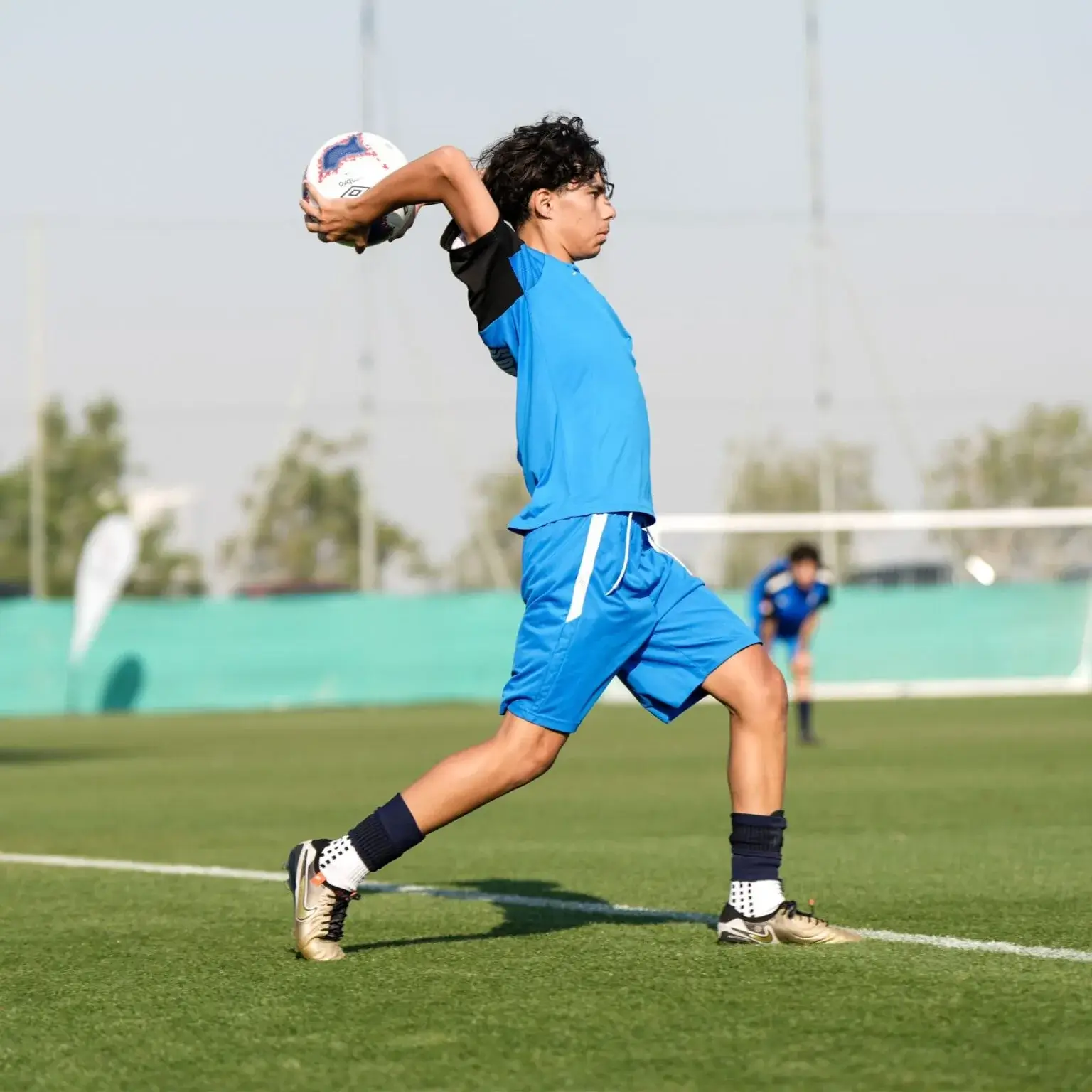 Man in blue shirt preparing to throw soccer ball | Mina Cup 2024.