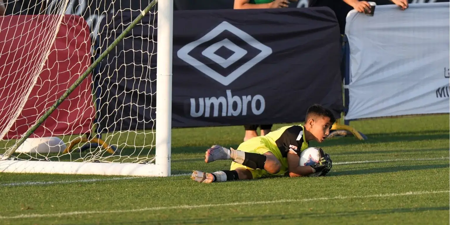 Soccer player lying on ground near goal, looking exhausted after Mina Cup 2024.