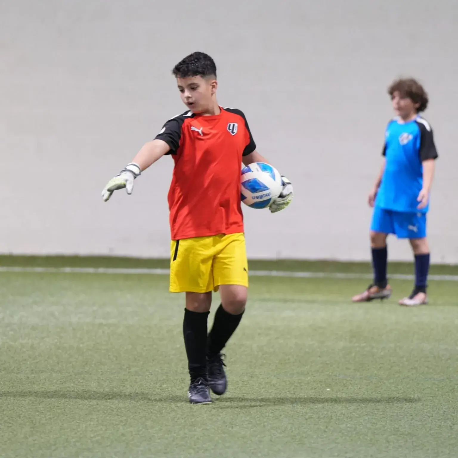 Young boy in football uniform holding ball, ready to play on the field of DOFA.