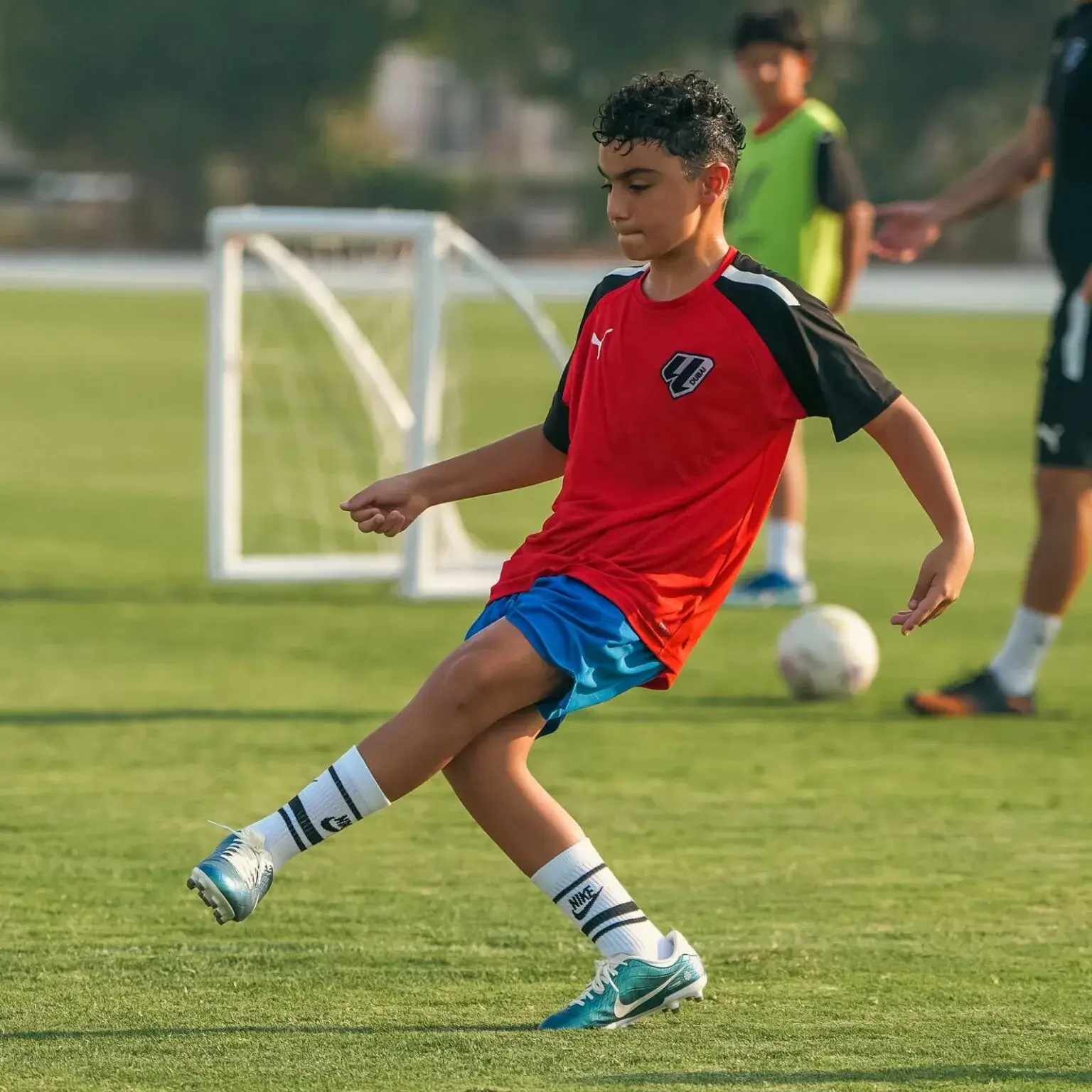 Young football player kicking a ball during a training session for IBER Cup competition.