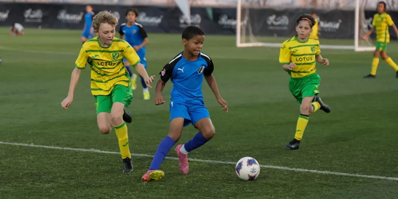 Young soccer players running and kicking the ball on the field | Mina Cup 2024.